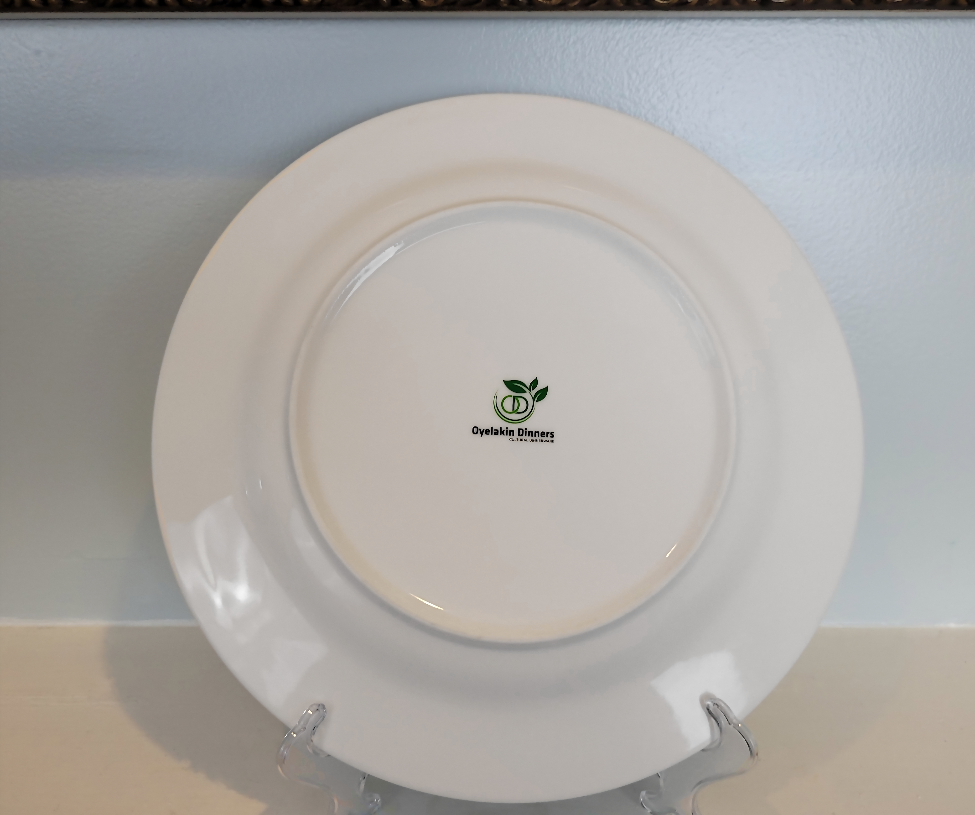 This is displaying the back of a dinner plate placed on a plate easel.  The back of the plate shows the brand logo 
